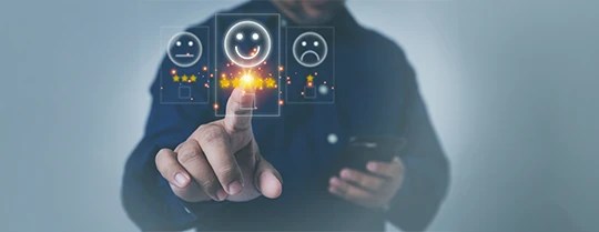 A person selecting a smiling face rating on a digital screen while holding a phone during mobile evaluation for telephone surveys.